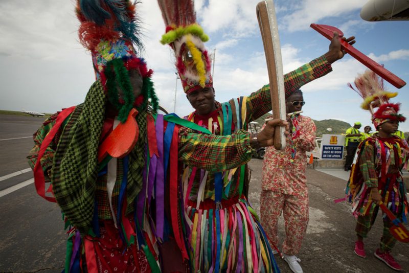 Masquerade dancers with the Baton to St Kitts and Nevis