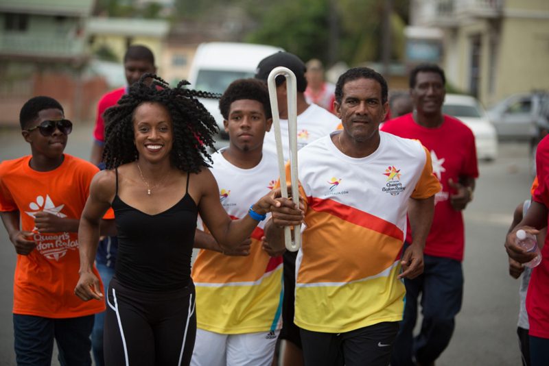 The Baton is carried by Deputy Premier Dr The Hon Kendrick Pickering and Olympic sprinter Tahesia Harrigan Scott 