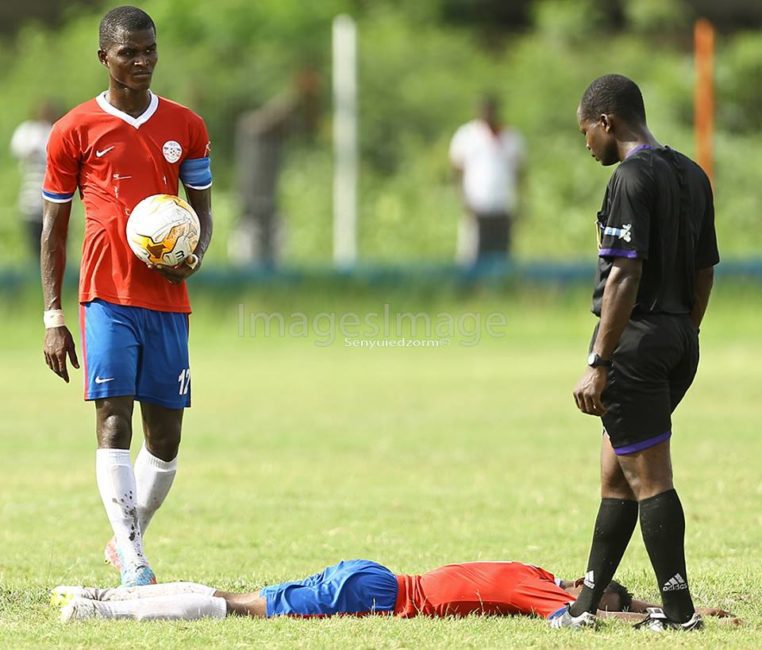 Tamimu lying on the turf as Samuel Sarfo goes for the ball